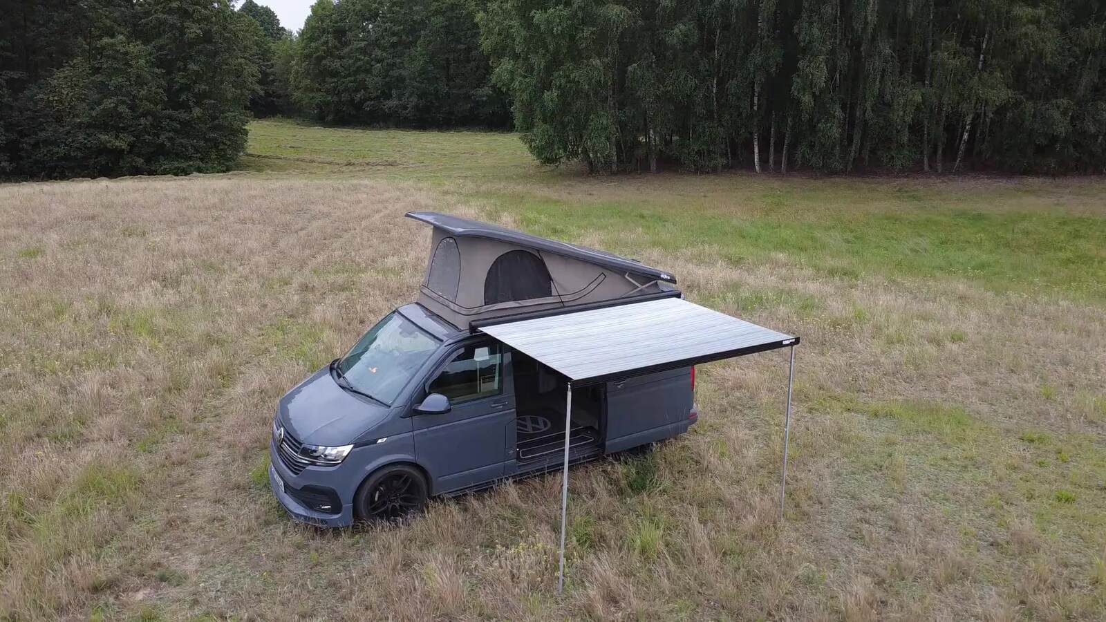 Aerial view of Vincent the VW T6.1 campervan camped in a meadow with pop-top roof raised and awning extended